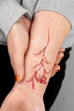 a woman's hand with a tattoo on her left arm and the image of a flower