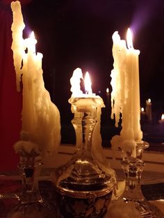 three lit candles sitting on top of a table next to an ornate glass vase and bowl