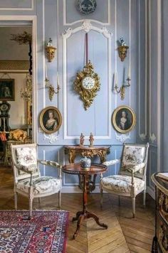 an ornate room with blue walls and antique furniture in the corner, including two chairs and a small table