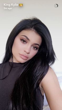 a woman with long black hair posing for the camera