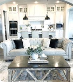 a living room filled with furniture and a kitchen in the backgroung area