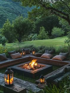 a fire pit surrounded by lots of pillows and lights in the middle of a field