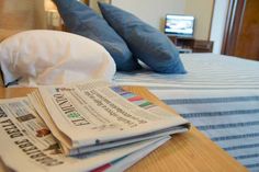 newspapers are stacked on top of each other on a bed with blue and white sheets