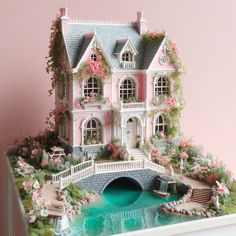 a doll house with flowers on the roof and bridge over water in front of it