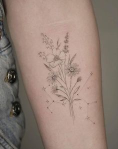 a woman's arm with flowers and stars tattooed on the back of her body