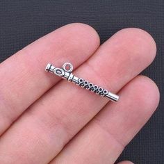 a person is holding a silver charm in their hand