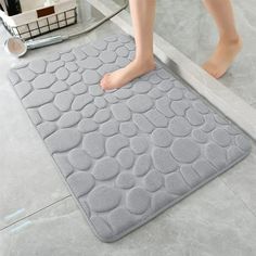 a person standing on a bathroom floor next to a bath mat with circles and dots