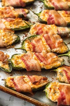 bacon and cheese stuffed jalapenos on a baking sheet