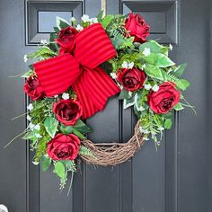 a wreath with red roses and greenery on the front door