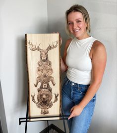 a woman standing next to a painting on a easel holding it up in front of her