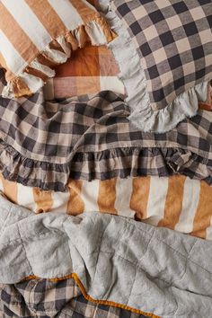 an unmade bed with plaid pillows and ruffles on the comforter is shown