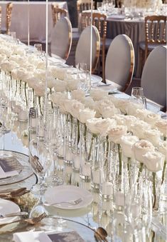 a long table is set with white flowers and place settings