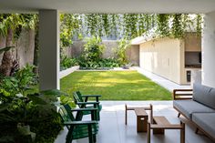 an outdoor living area with green furniture and plants on the walls, grass in the background