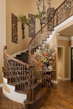 an elegant staircase with wrought iron railing and wood flooring in a home, decorated with flowers