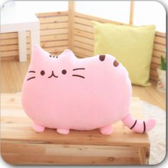 a pink cat pillow sitting on top of a wooden table