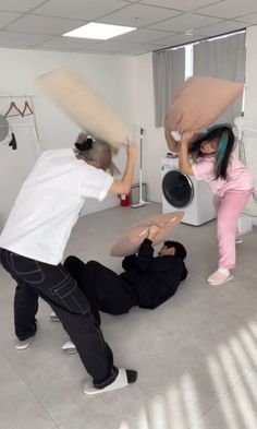 two people are playing with pillows in an empty room