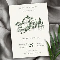 the save the date card is sitting on top of a blanket with a pine tree