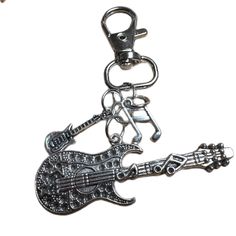 a guitar keychain with music notes on the neck and an electric guitar charm attached to it