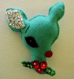 a green stuffed animal with red berries on it's nose and ears is hanging from the wall