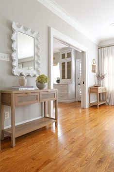 a white room with wood floors and a large mirror on the wall above the table