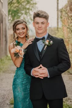 a man in a tuxedo standing next to a woman wearing a blue dress