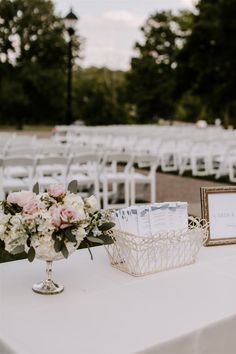 an arrangement of flowers and cards on a table at a wedding ceremony with chairs in the background