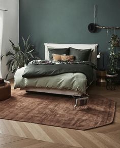 a large bed sitting on top of a hard wood floor next to a green wall