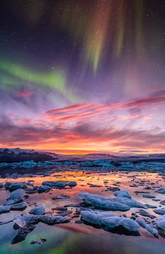 the aurora bore is seen over ice and water in this colorful sunset photo taken on an icy