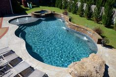 an above ground swimming pool surrounded by rocks and water features a waterfall that flows into it