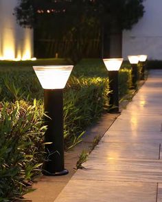 several lights that are sitting on the ground near some grass and bushes in front of a building