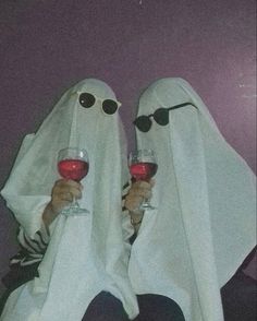 two people dressed as ghost holding wine glasses