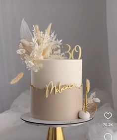 a white cake with gold lettering and feathers on the top that says'30th '