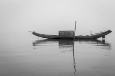 a small boat floating on top of a lake in the middle of foggy weather