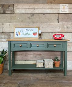 a green table with two drawers and a sign on top that says farmer market next to potted plants