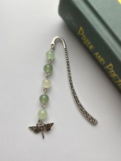 a bookmark with a dragonfly charm attached to it next to a green book