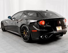 a black sports car is parked in a room with white walls and tile flooring