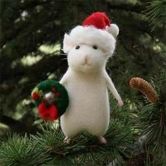 a white cat ornament hanging from a pine tree with a wreath on it