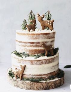 a three tiered cake decorated with deer figurines and pine trees on top