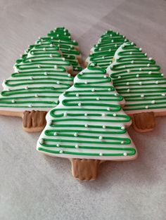 decorated cookies in the shape of christmas trees on a white tablecloth with green and white icing