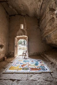 a chair sitting on top of a rug in the middle of a stone room with an open door