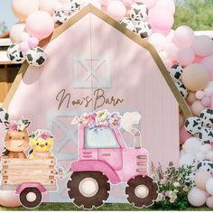 a pink tractor with balloons and farm animals on the back is parked in front of a barn