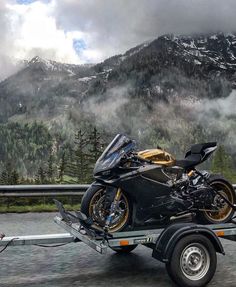 a motorcycle is being towed on the back of a trailer with mountains in the background