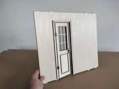 a hand is holding an open book with a door on the front and side sides