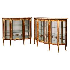 a pair of antique china cabinets with glass doors and gold leaf trimmings, each side - by - side