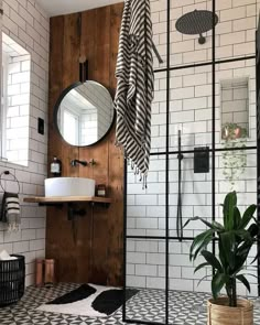 a bathroom with black and white tiles, a wooden door, a mirror and a potted plant