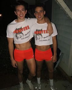 two young men standing next to each other in red shorts and white t - shirts