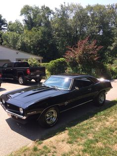 a black muscle car parked in front of a house