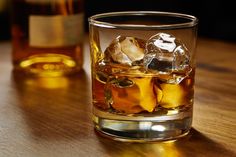 a glass filled with ice sitting on top of a wooden table