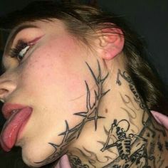 a woman with tattoos on her neck and chest is sticking out her tongue to the side