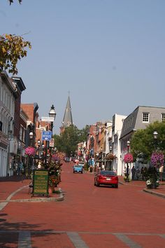 a red car driving down a street next to tall buildings